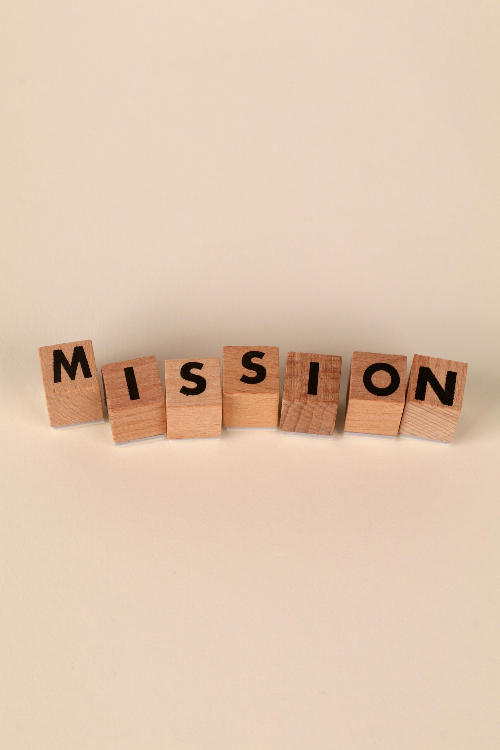Wooden blocks with letters spelling 'Mission' on a soft neutral background, ideal for business themes.