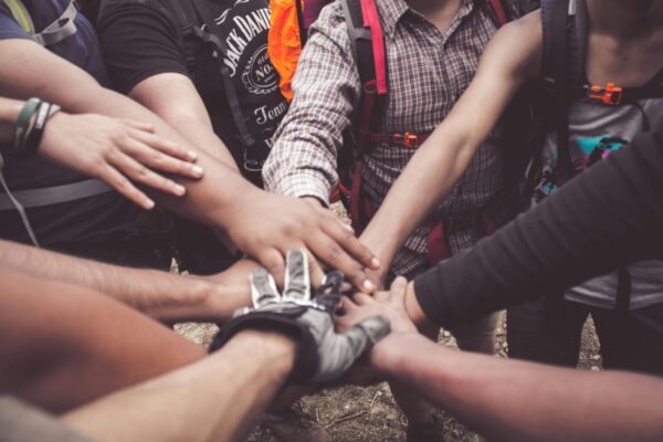 Building Momentum Together A group of diverse individuals join hands for teamwork