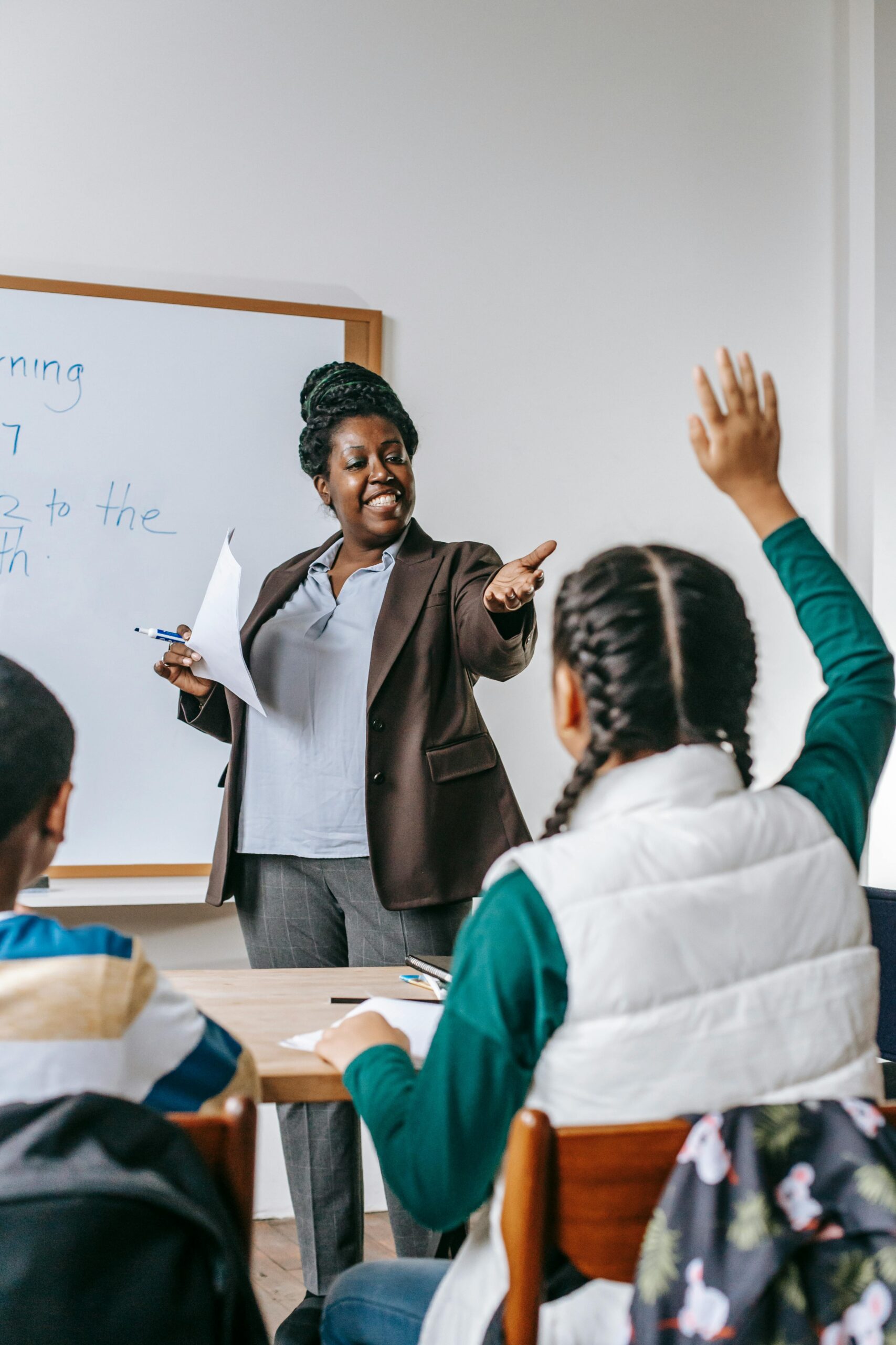 About Smiling African American woman offering schoolgirl to ask question during lesson in school classroom