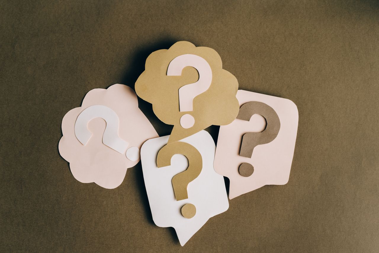 Why PAG Is Asking Questions Four paper cutouts of question marks in beige and white on a brown surface, symbolizing inquiry and curiosity.